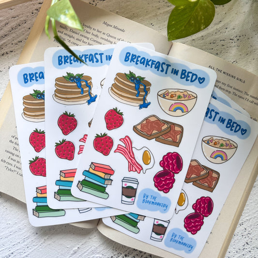 Set of 'Breakfast in Bed' themed stickers on a book with a plant in the background.