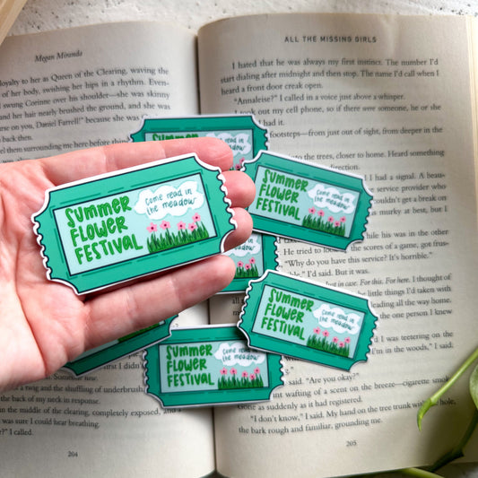 Hand holding 'Summer Flower Festival' stickers over an open book