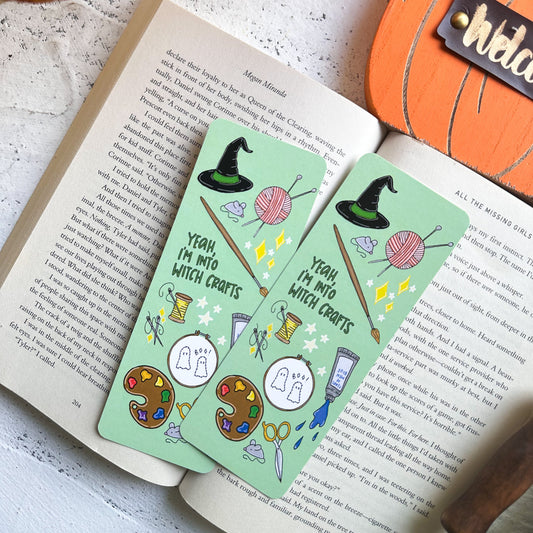 Two green bookmarks with Halloween-themed illustrations on an open book.