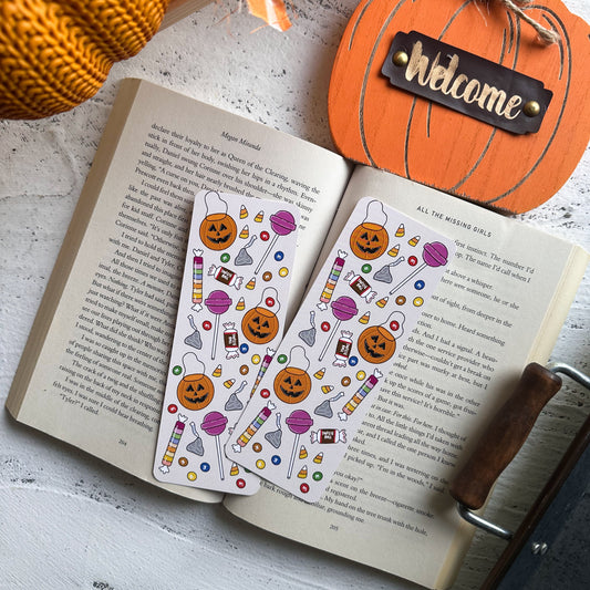 Open book with Halloween-themed stickers and decorative pumpkin on a light surface.